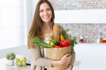beautiful-young-woman-with-vegetables-in-grocery-bag-at-home