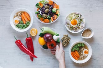 crop-hand-putting-vegetables-near-dishes_23-2147778296