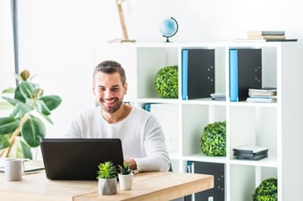 smiling-young-businessman-using-laptop-in-office_23-2147839980